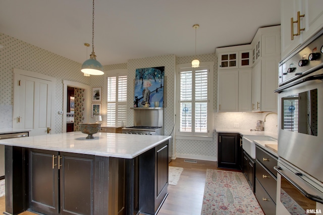 1477 Maine St, Quincy, IL 62301 - kitchen featuring white cabinetry, wallpapered walls, a sink, dishwasher, and wood finished floors