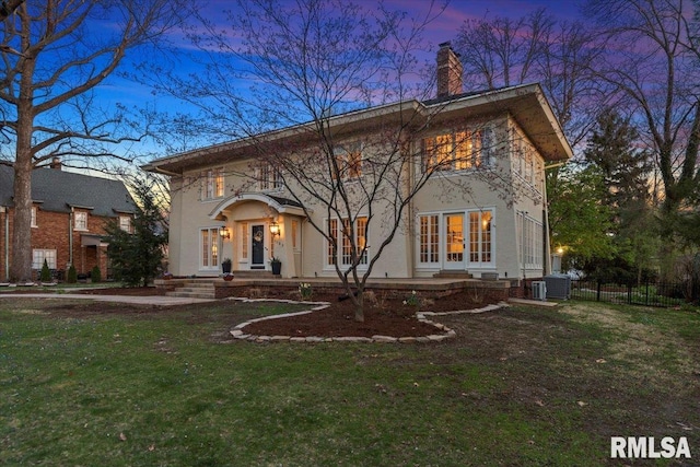 view of front of home with a chimney, a front yard, fence, french doors, and central AC unit