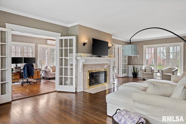 living room with ornamental molding, a wall mounted AC, wood finished floors, french doors, and a premium fireplace