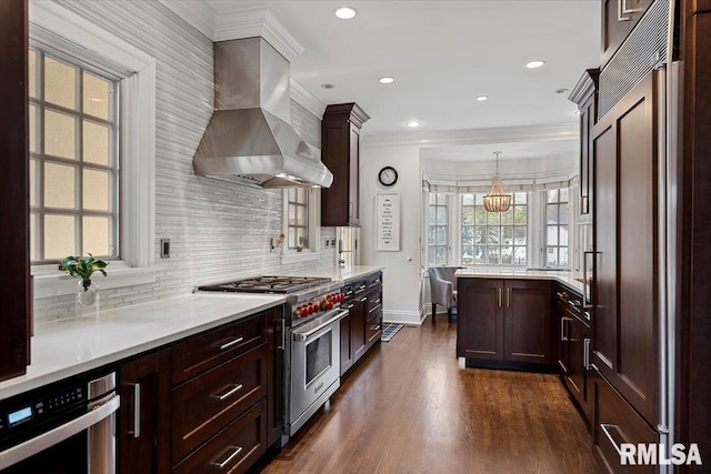 kitchen featuring light countertops, high quality appliances, extractor fan, and backsplash