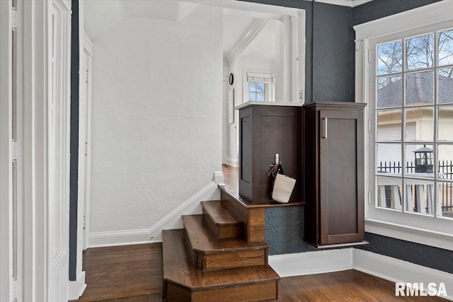 staircase featuring wood finished floors, a textured wall, and baseboards
