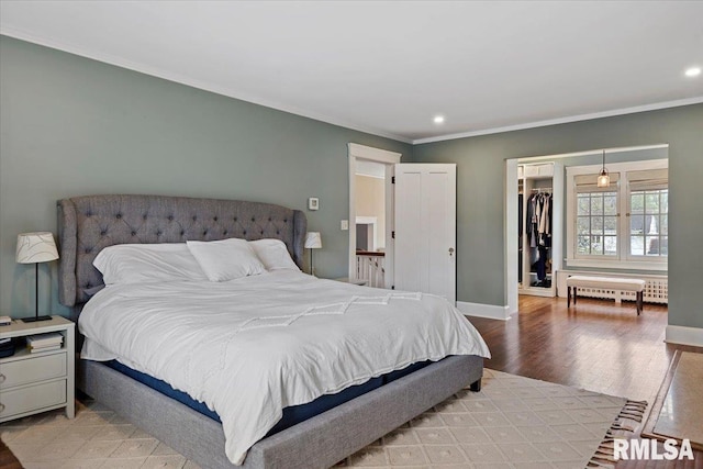 bedroom featuring crown molding, a walk in closet, recessed lighting, and light wood-style floors