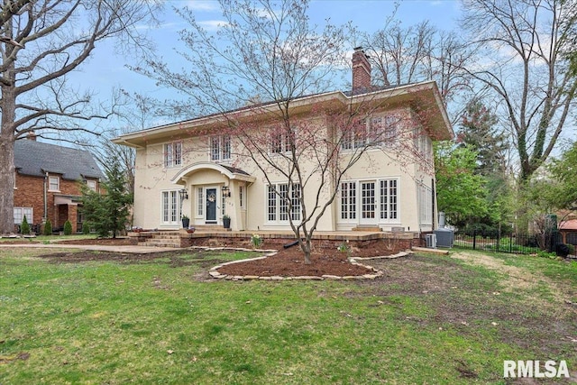 rear view of property featuring a chimney, french doors, central AC, fence, and a lawn