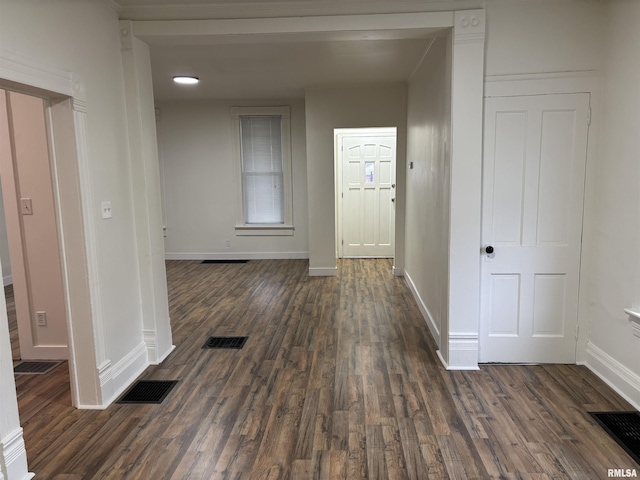 corridor with dark wood-type flooring, baseboards, and visible vents