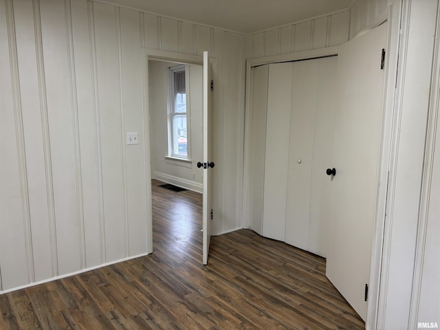 unfurnished bedroom with dark wood-style floors and a closet