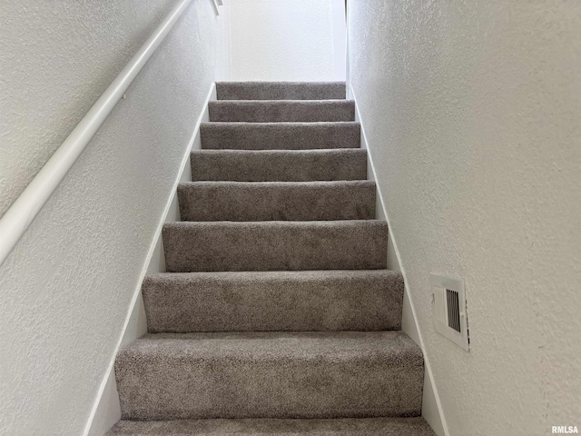 stairway featuring a textured wall and visible vents