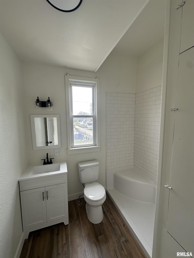 bathroom featuring toilet, vanity, wood finished floors, walk in shower, and baseboards