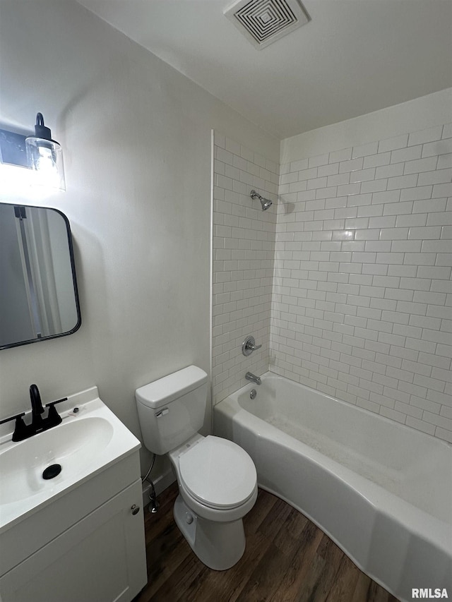 bathroom with visible vents, toilet, wood finished floors, vanity, and shower / bathing tub combination