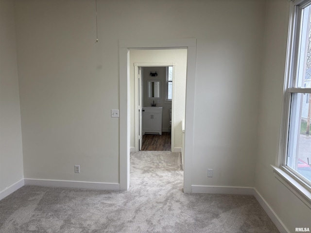 spare room featuring carpet floors, plenty of natural light, and baseboards