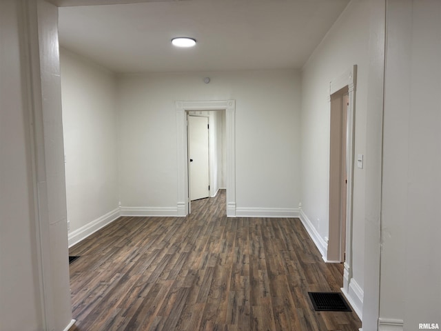 unfurnished room with baseboards, dark wood-style floors, and visible vents