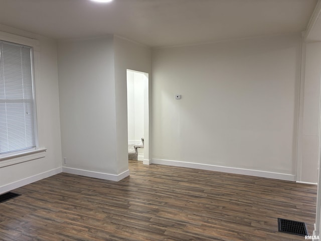 spare room featuring dark wood-type flooring, baseboards, and visible vents