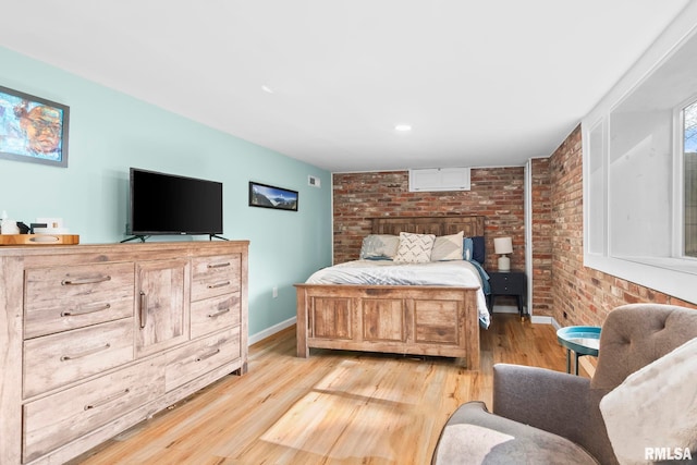 bedroom featuring visible vents, light wood-style flooring, baseboards, and brick wall