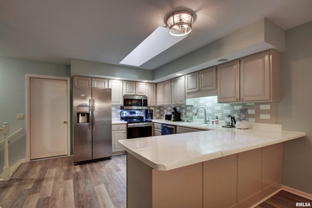 624 Pawn Ave, Quincy, IL 62305 - kitchen featuring tasteful backsplash, light countertops, appliances with stainless steel finishes, a peninsula, and a skylight