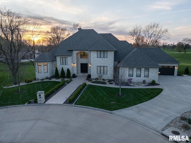 2300 Greenspointe Cir, Quincy, IL 62301 - french country style house featuring stone siding, a shingled roof, a yard, and concrete driveway