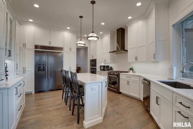 2300 Greenspointe Cir, Quincy, IL 62301 - kitchen featuring built in appliances, wall chimney range hood, a kitchen breakfast bar, light wood-type flooring, and white cabinetry
