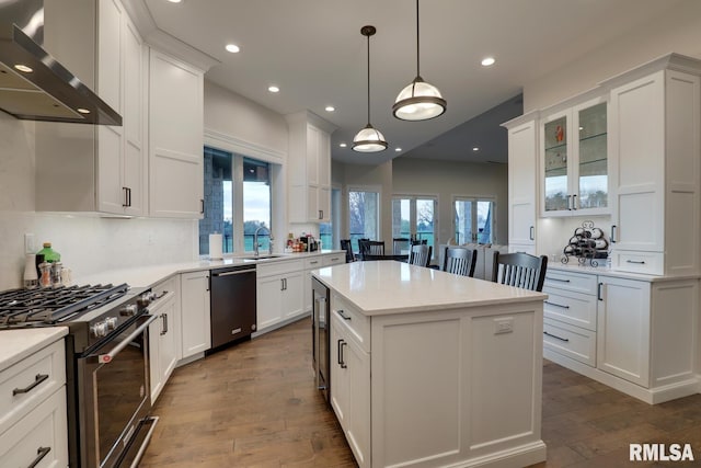 2300 Greenspointe Cir, Quincy, IL 62301 - kitchen with dishwashing machine, wall chimney range hood, gas range, white cabinets, and dark wood-type flooring