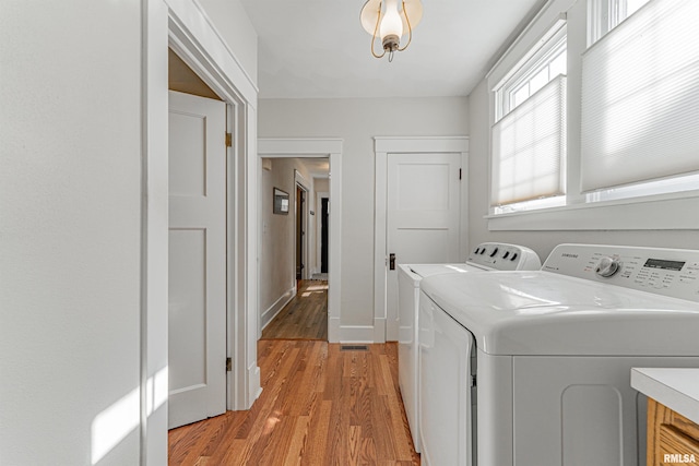 washroom with laundry area, baseboards, light wood-type flooring, and washer and clothes dryer