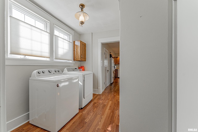 laundry room with washer and dryer, light wood-type flooring, baseboards, and cabinet space