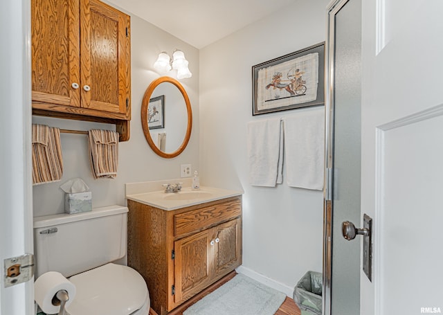 bathroom featuring toilet, vanity, and baseboards