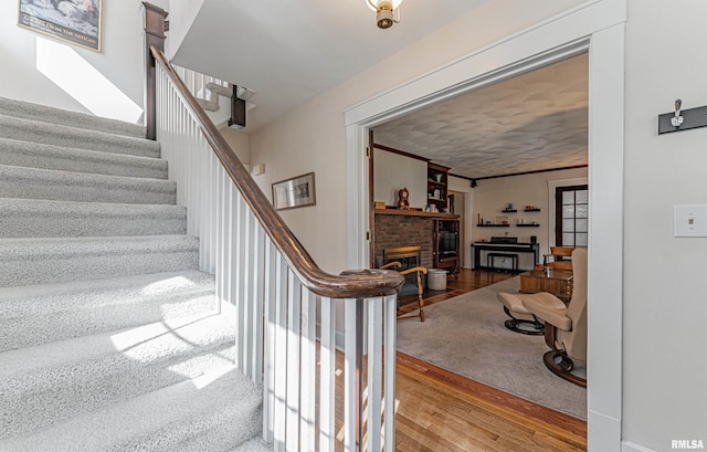 staircase featuring wood finished floors and a fireplace