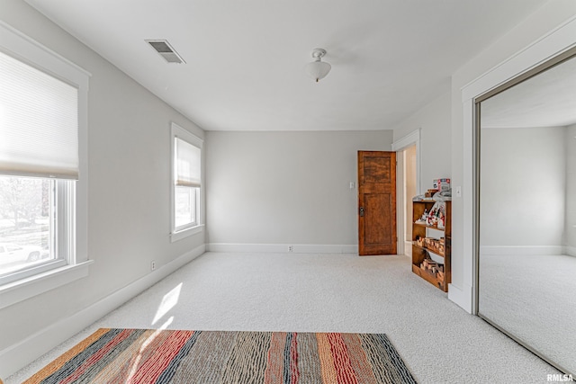carpeted empty room featuring baseboards and visible vents