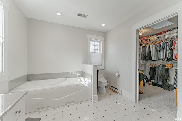 bathroom with a baseboard heating unit, tile patterned floors, toilet, visible vents, and a garden tub