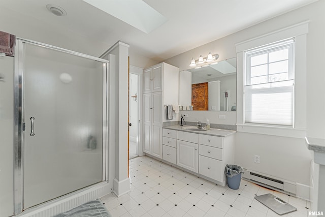 bathroom with a skylight, baseboard heating, vanity, tile patterned floors, and a stall shower