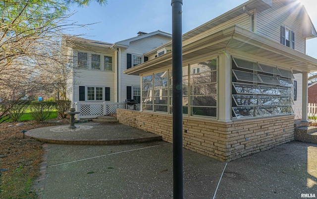 view of side of home with a sunroom and brick siding