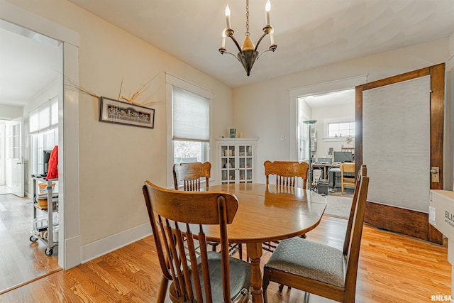 dining space with baseboards, an inviting chandelier, and light wood-style floors