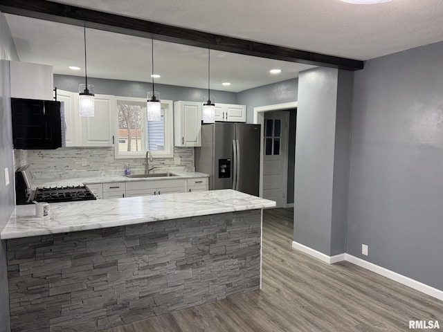 kitchen featuring range, a peninsula, a sink, stainless steel fridge, and backsplash