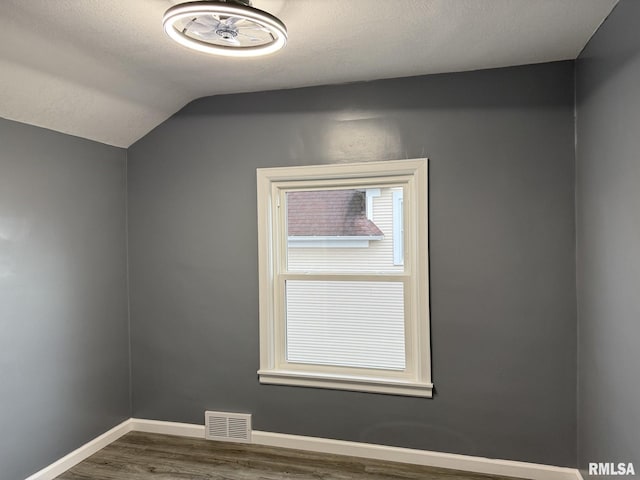bonus room featuring baseboards, vaulted ceiling, dark wood-style floors, a textured ceiling, and visible vents