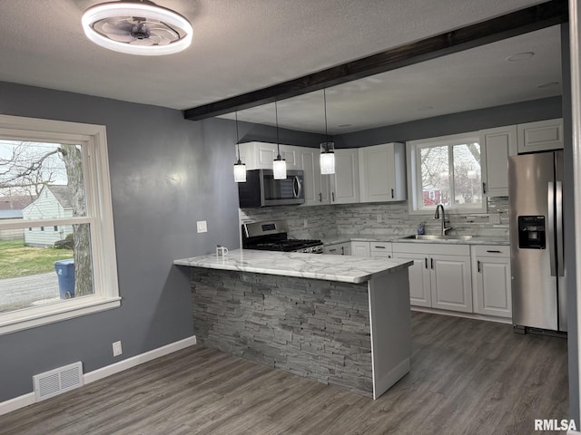 kitchen featuring visible vents, appliances with stainless steel finishes, a sink, backsplash, and beam ceiling