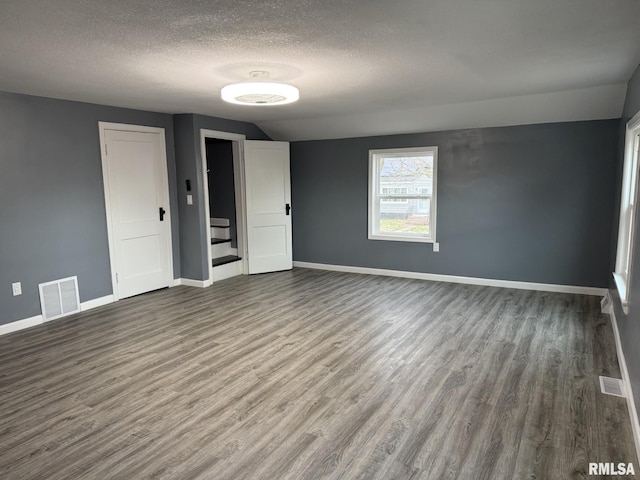 spare room with visible vents, baseboards, wood finished floors, and a textured ceiling