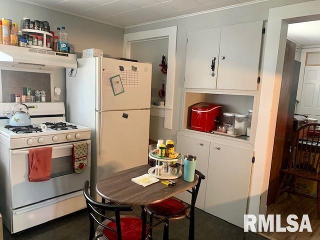kitchen with white cabinets, crown molding, under cabinet range hood, and white appliances
