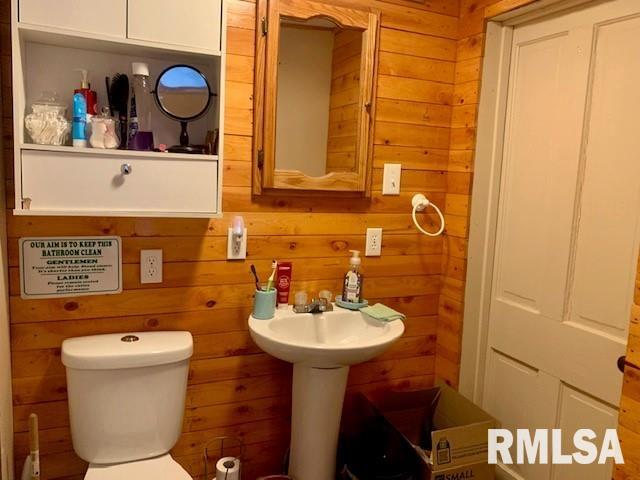 half bathroom with wood walls and toilet