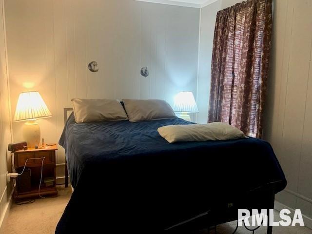 bedroom with crown molding, carpet, and a decorative wall