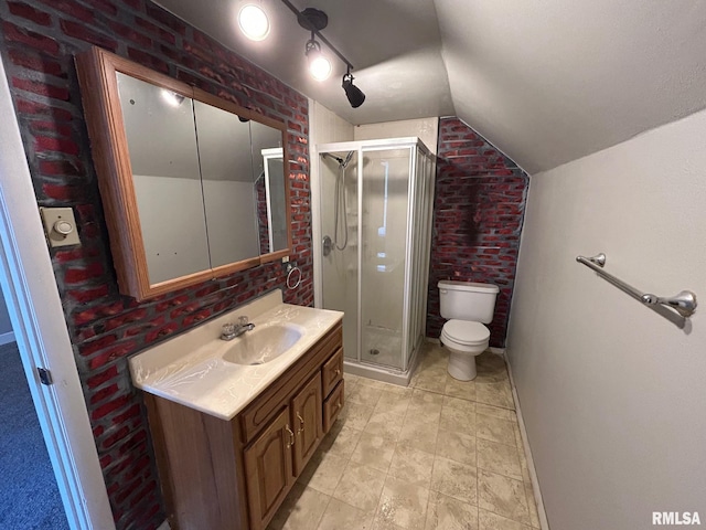 bathroom with brick wall, toilet, vanity, vaulted ceiling, and a stall shower