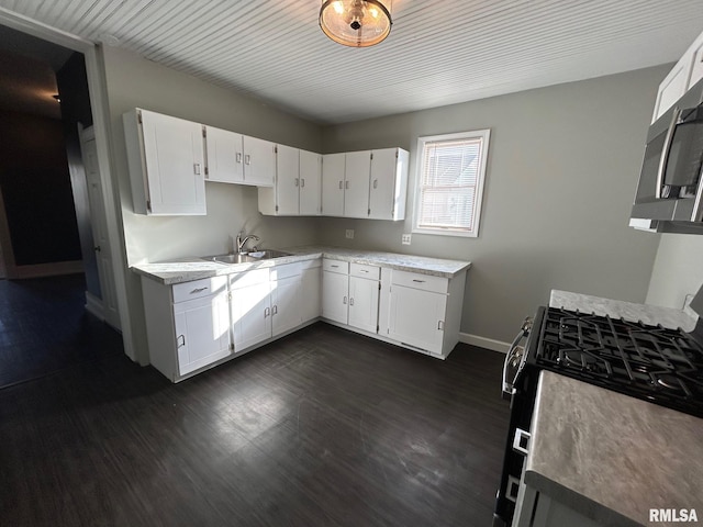 kitchen with light countertops, dark wood-style flooring, a sink, and baseboards
