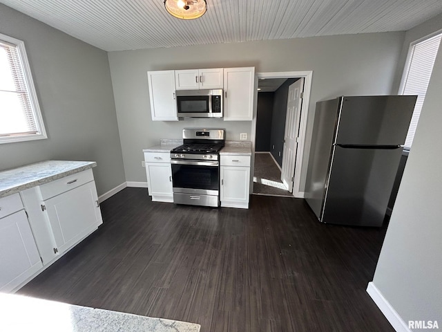 kitchen with baseboards, light stone counters, white cabinetry, dark wood finished floors, and stainless steel appliances