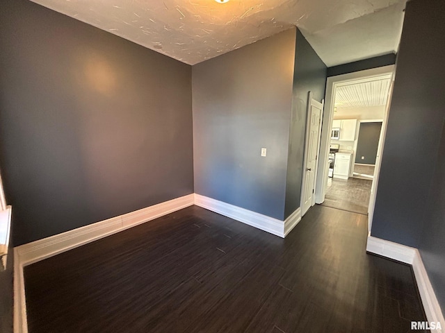 unfurnished room with dark wood-style flooring and baseboards