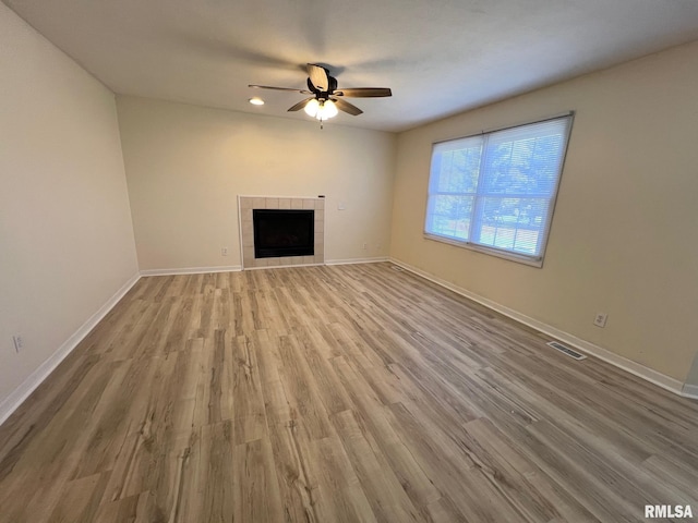 905 W Wind Rose Ln, Athens, IL 62613 - unfurnished living room featuring baseboards, a tiled fireplace, visible vents, ceiling fan, and wood finished floors