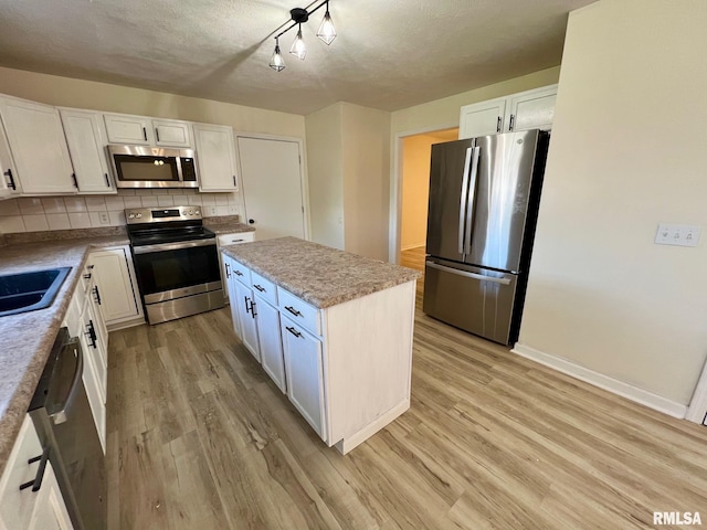 905 W Wind Rose Ln, Athens, IL 62613 - kitchen with appliances with stainless steel finishes, light wood finished floors, backsplash, and white cabinets