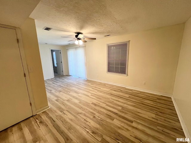 905 W Wind Rose Ln, Athens, IL 62613 - unfurnished room with light wood-type flooring, a textured ceiling, a ceiling fan, visible vents, and baseboards