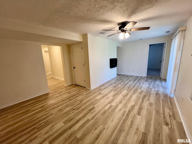 905 W Wind Rose Ln, Athens, IL 62613 - unfurnished living room featuring light wood-style flooring, a textured ceiling, a ceiling fan, and visible vents