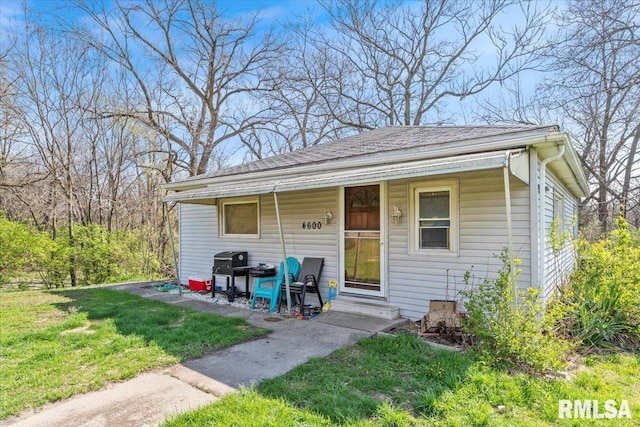 exterior space featuring a shingled roof and a front lawn