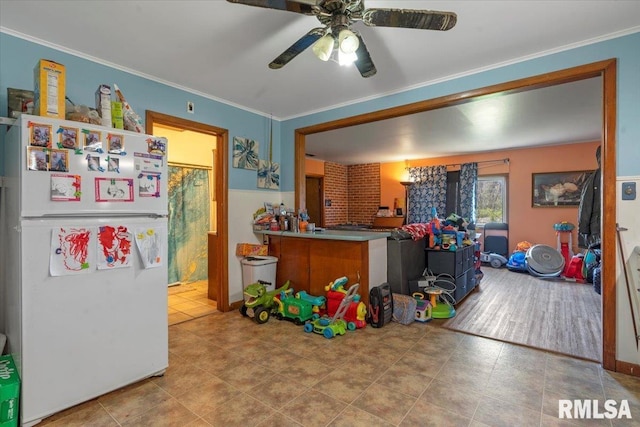 interior space with crown molding, tile patterned floors, ceiling fan, and freestanding refrigerator