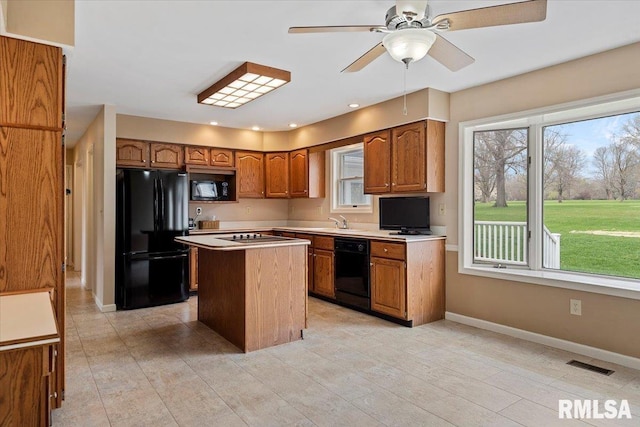 kitchen with visible vents, a center island, light countertops, brown cabinets, and black appliances