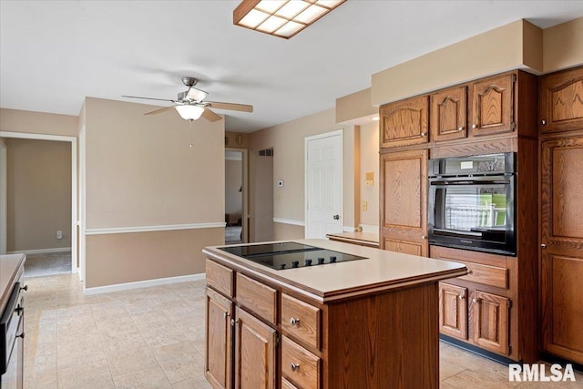 kitchen with baseboards, a kitchen island, brown cabinetry, ceiling fan, and black appliances