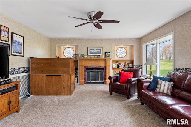 living room featuring ceiling fan, carpet flooring, a glass covered fireplace, and wallpapered walls