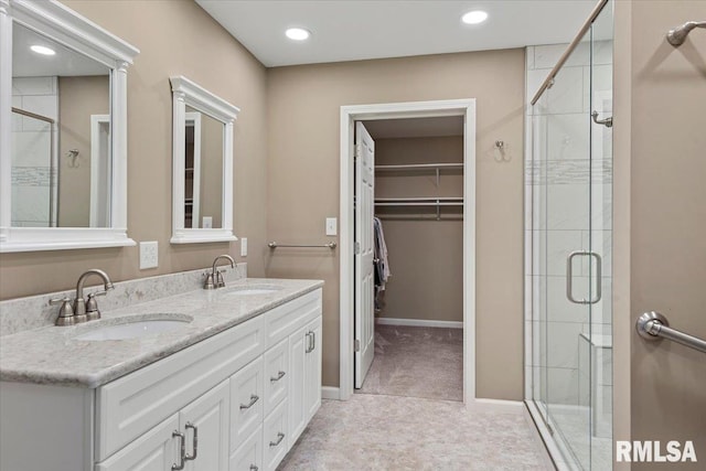 bathroom with a shower stall, a sink, a walk in closet, and recessed lighting
